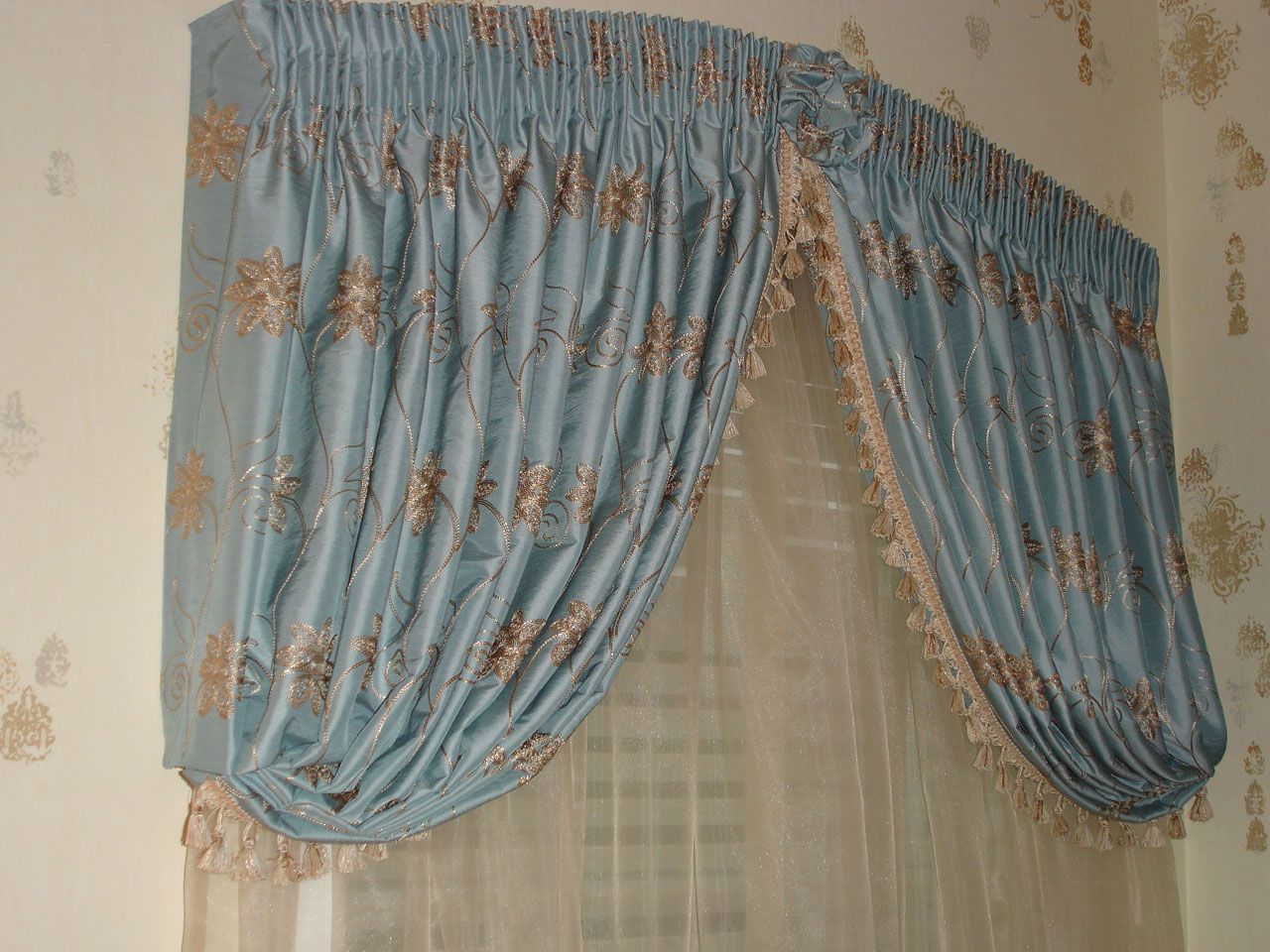 Blue curtain with gold floral embroidery and scalloped edge, above a sheer white curtain.