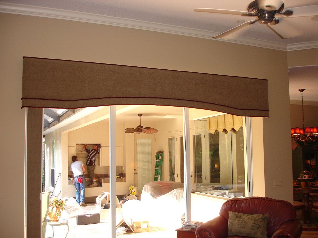 A partially open doorway with a brown shade, overlooking a room with a person and furniture.