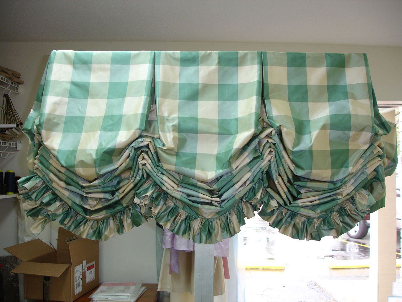 Green and white checkered valance with ruffled bottom, hanging above a window.