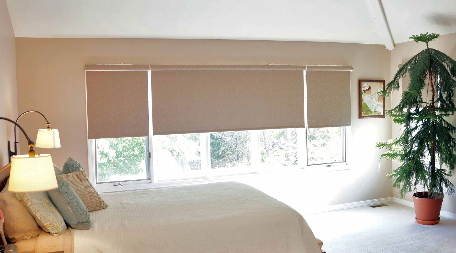 A bedroom with a bed , lamps , and a potted plant.