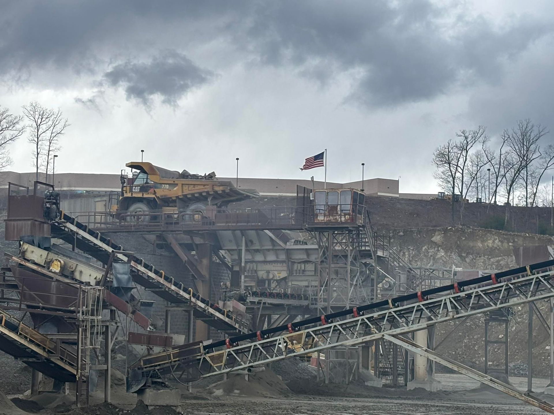 Damaged industrial structure with conveyor belts and a Canadian flag under a cloudy sky