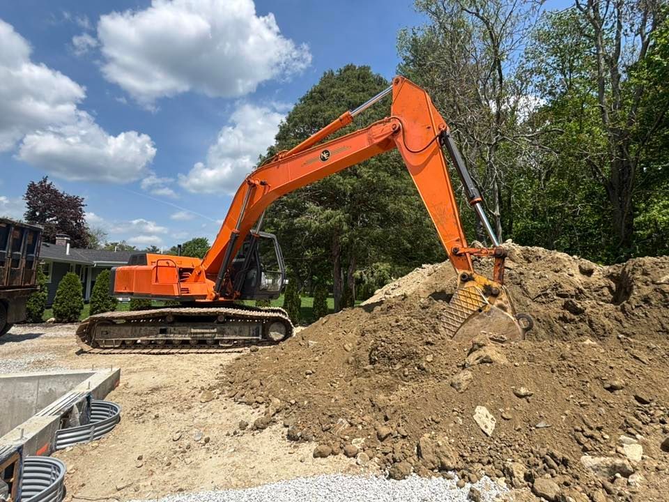Orange excavator digging a dirt pile at a construction site under a blue sky