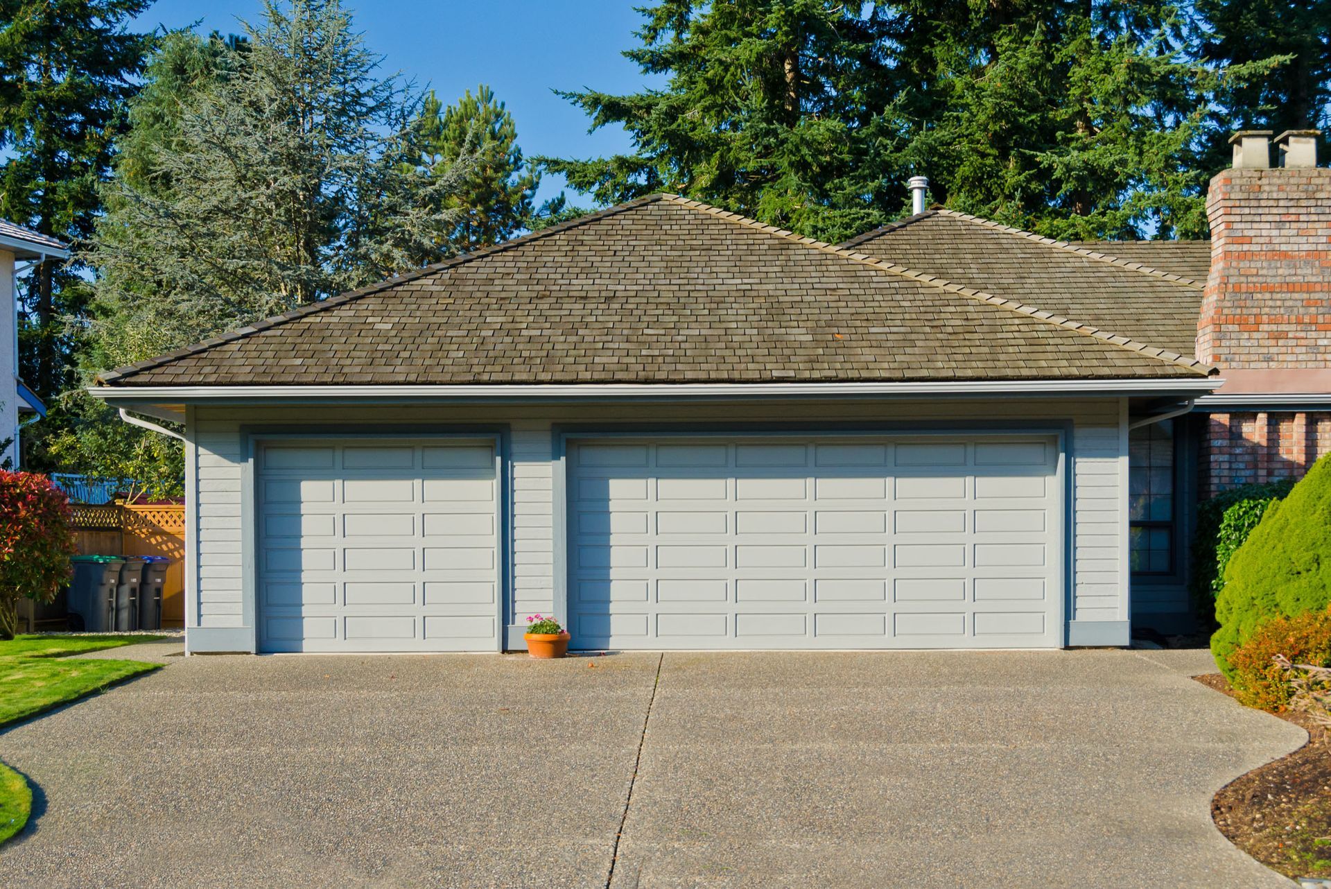 Two-car garage with light gray doors and a weathered gray roof; concrete driveway.