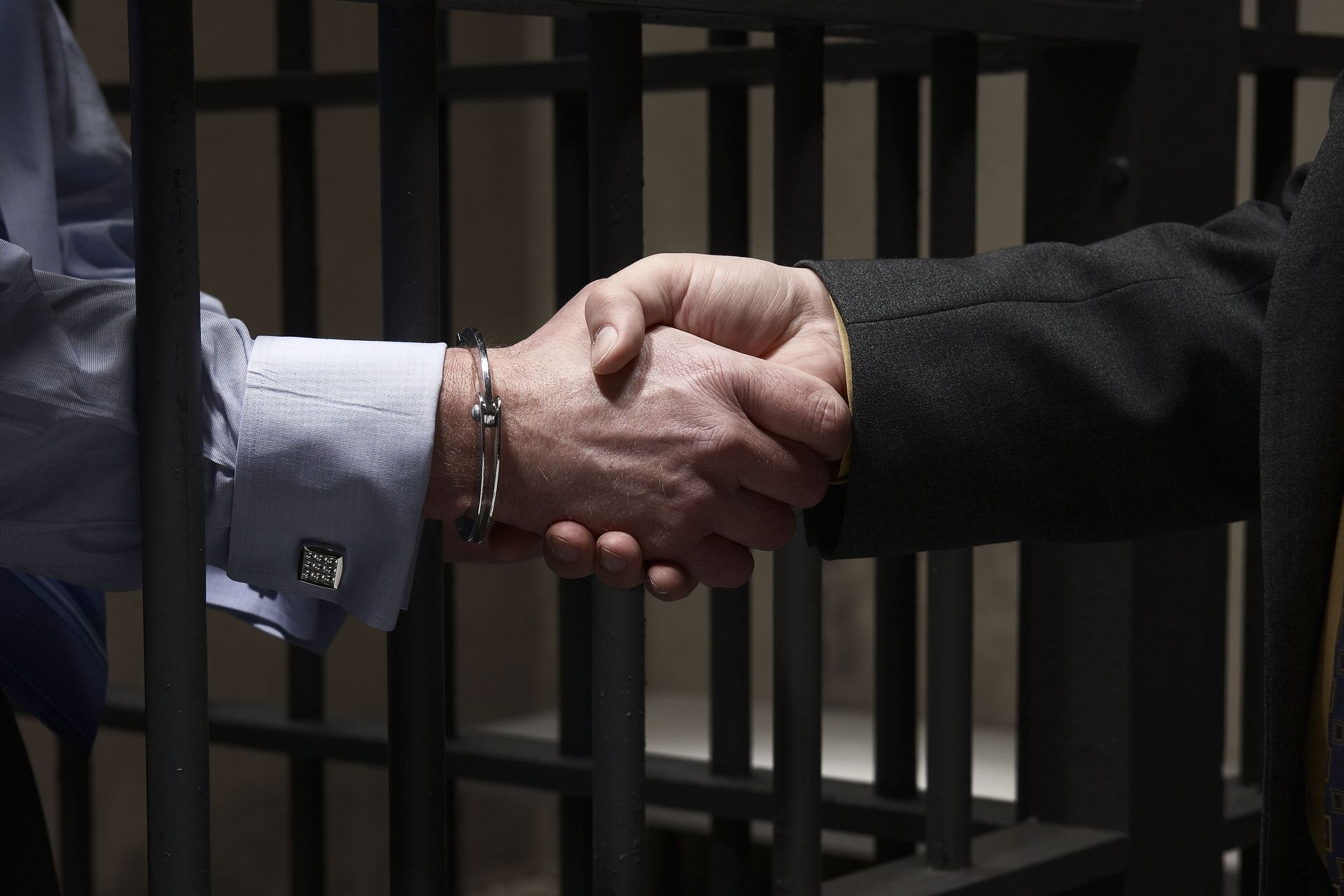 Two men shaking hands in front of a prison cell