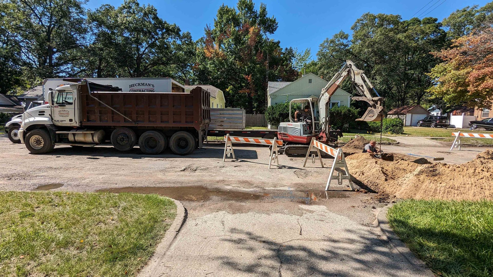 Construction site with a truck and excavator digging in a street.