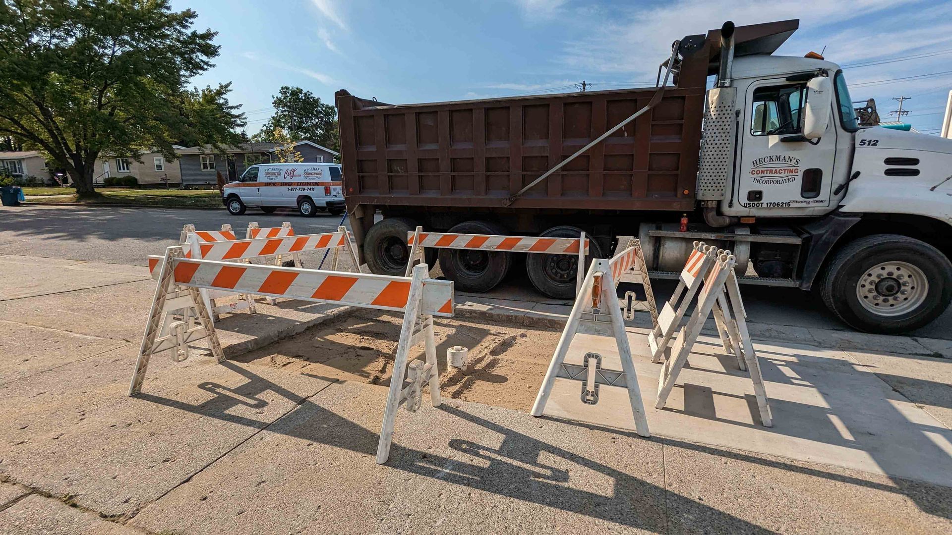 Road work scene: Dump truck parked behind traffic barriers. White, orange striped barriers on a concrete surface.