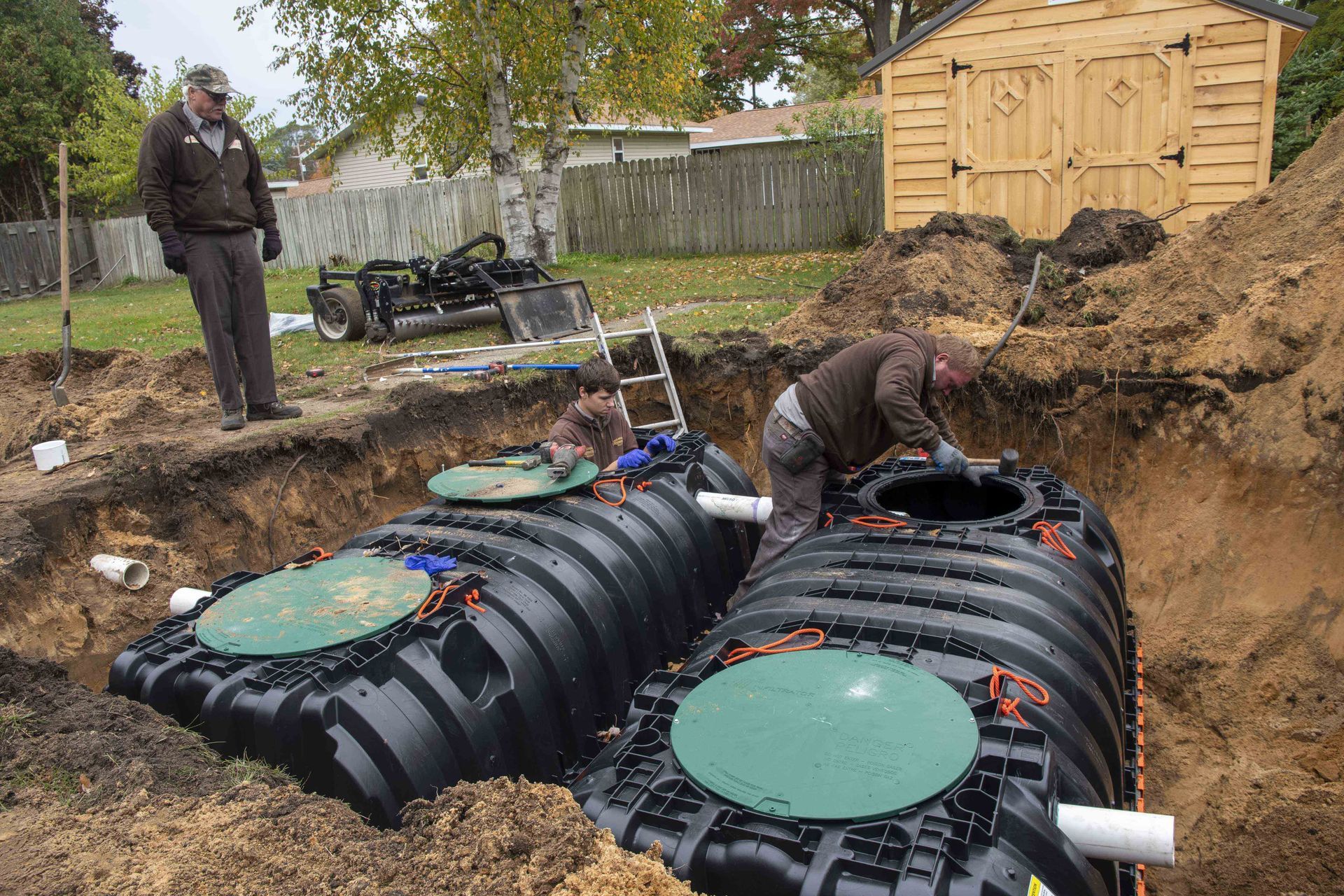 Two workers installing septic tanks in a residential yard.