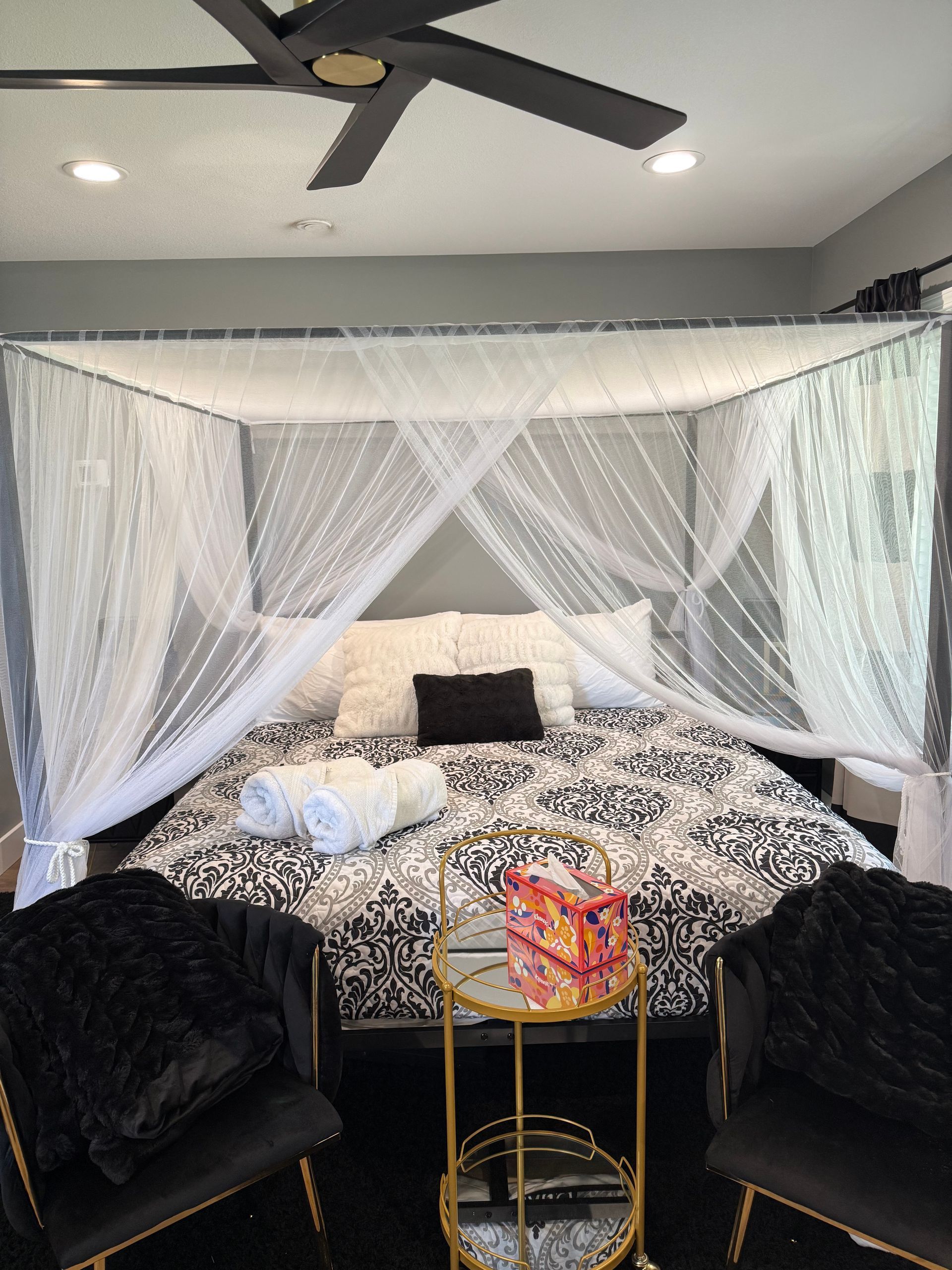 A bedroom with a canopy bed and a ceiling fan