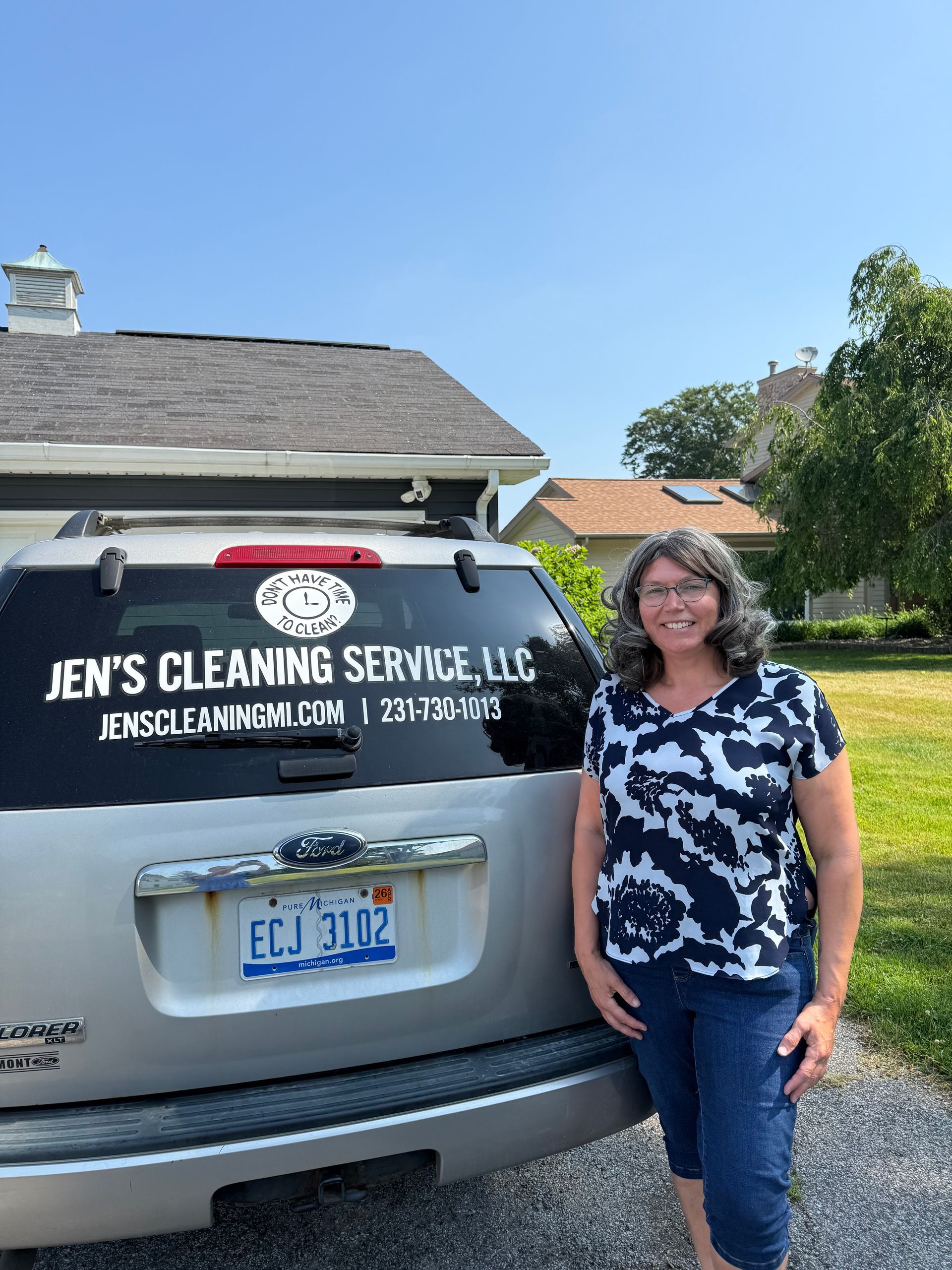 A woman is standing in front of a cleaning service vehicle.