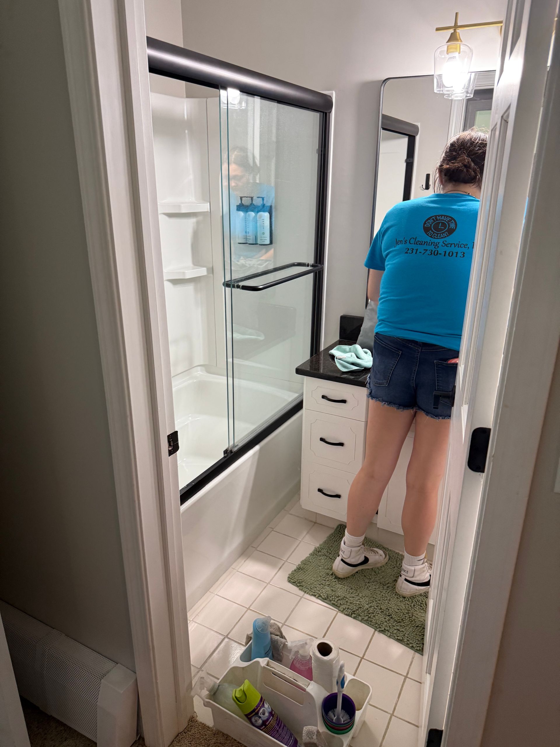 A woman in a blue shirt is cleaning a bathroom.