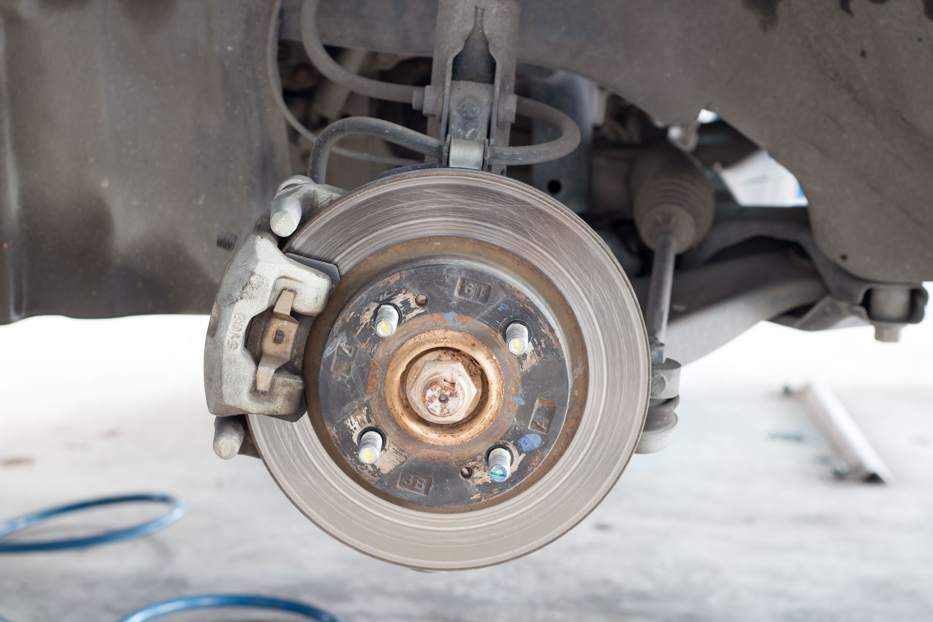 Car brake rotor with caliper and suspension components.