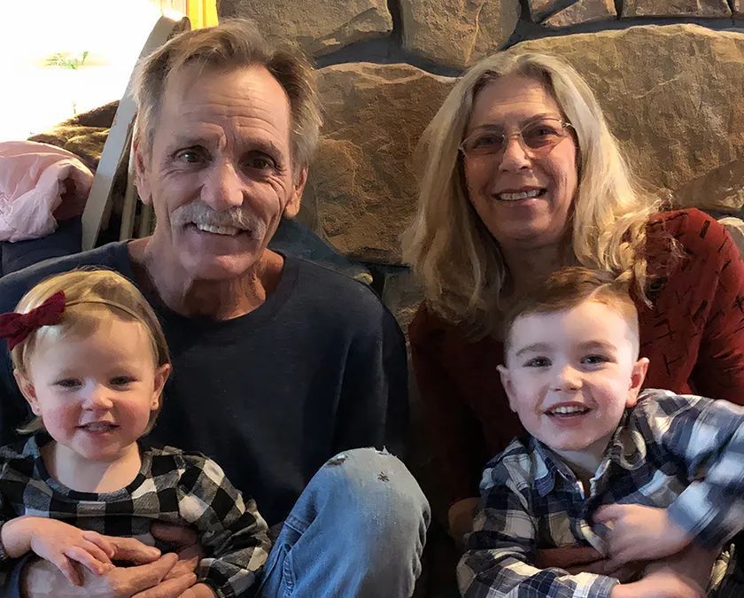 A family is posing for a picture in front of a fireplace.