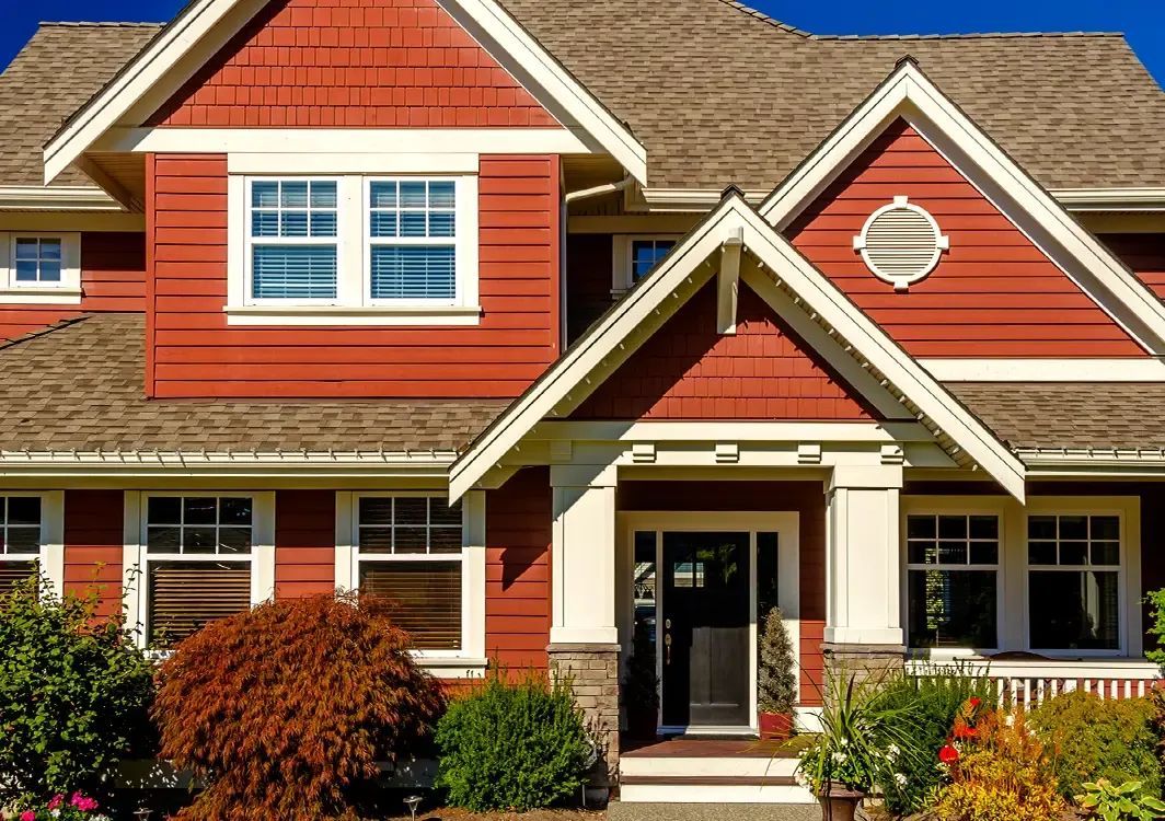 A large red and white house with a roof and a lot of windows.