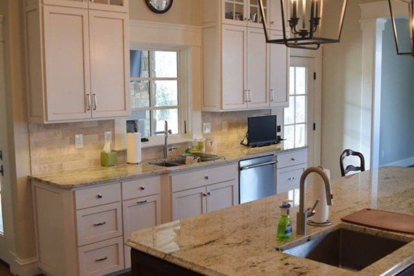 A kitchen with white cabinets , granite counter tops , a sink and a dishwasher.