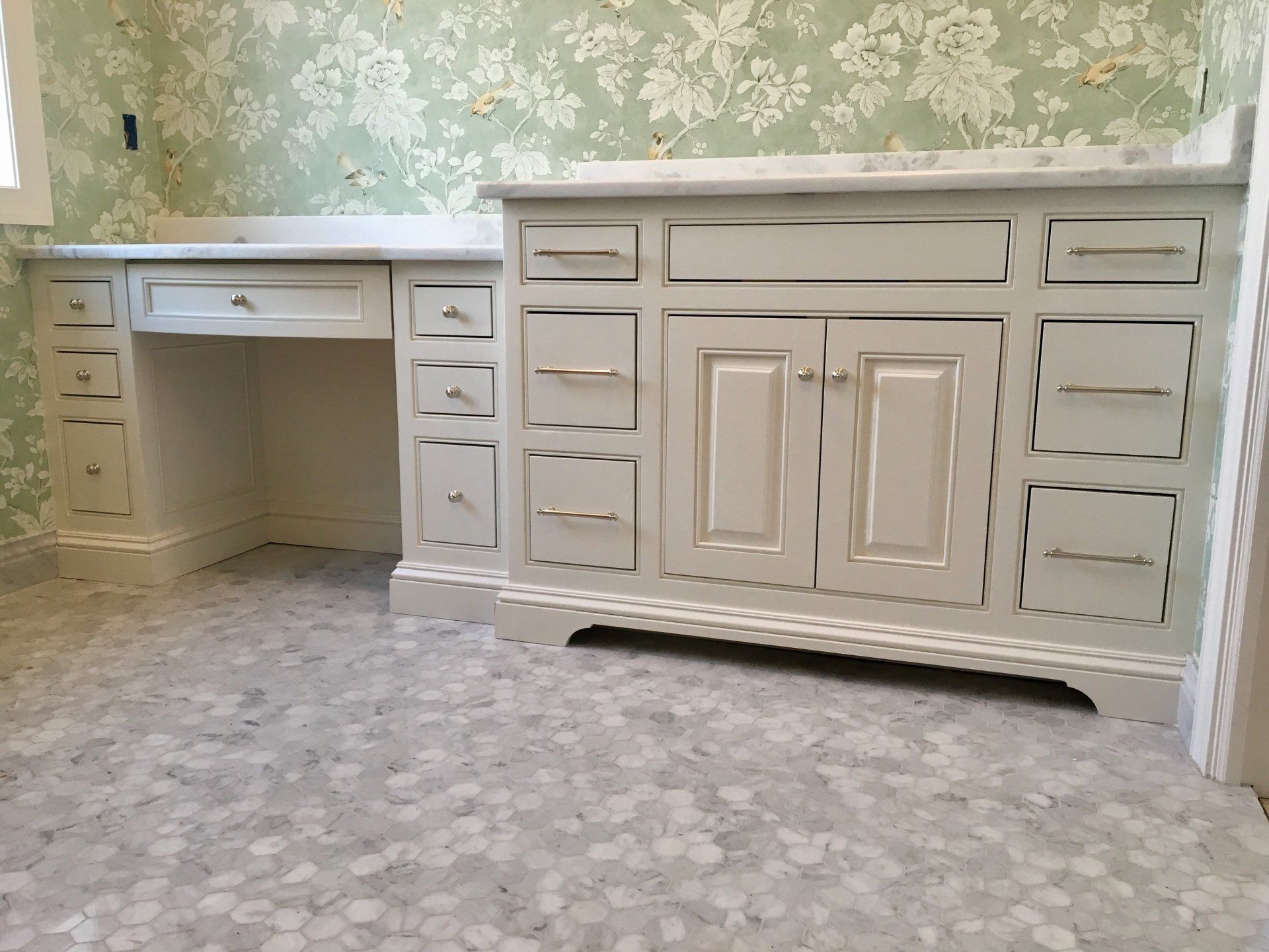 A bathroom vanity with drawers and a desk underneath it.