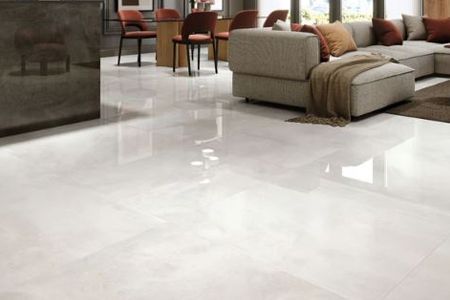 A living room with a couch and chairs and a white tile floor.