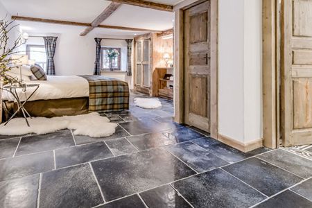 A bedroom with a king size bed and a tiled floor.