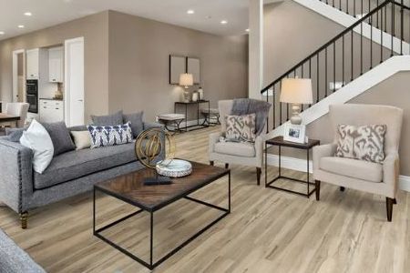 A living room with a couch , chairs , coffee table and stairs.