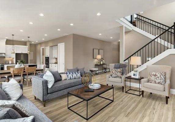 A living room with a couch , chairs , coffee table and stairs.