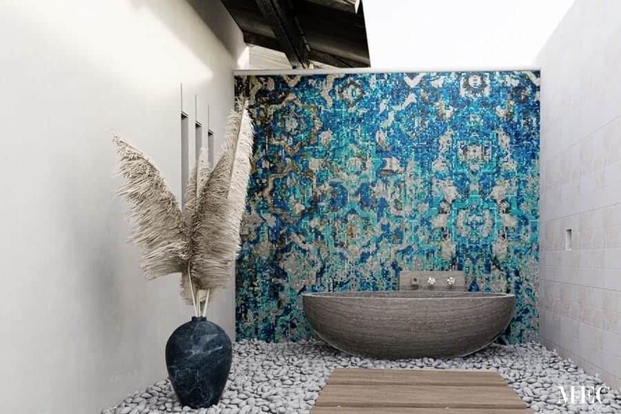 A bathroom with a bathtub and a vase of dried flowers.