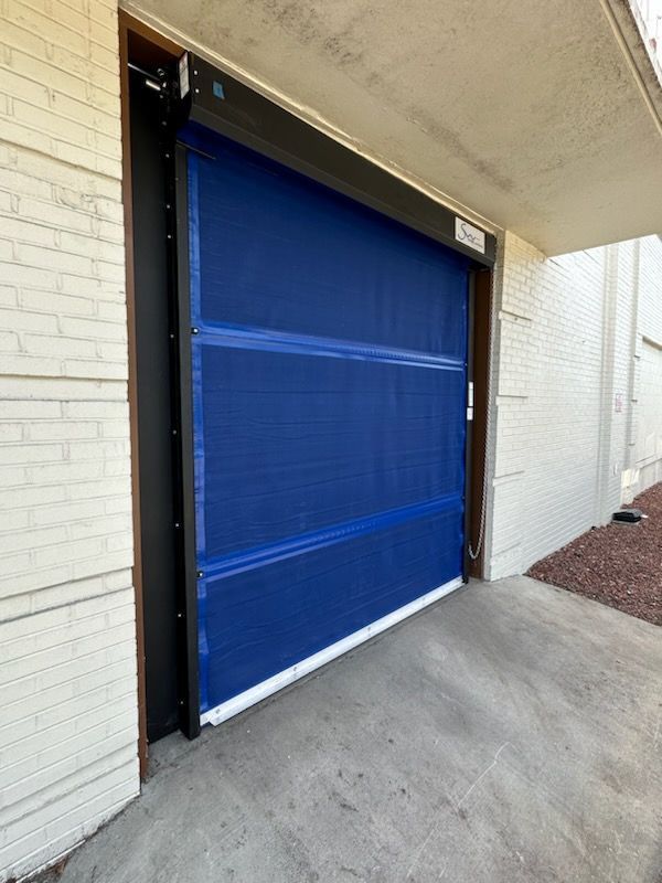 A blue garage door is sitting on the side of a building.