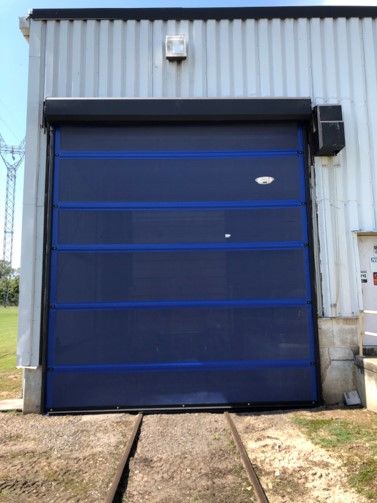 A blue garage door is open on the side of a building.