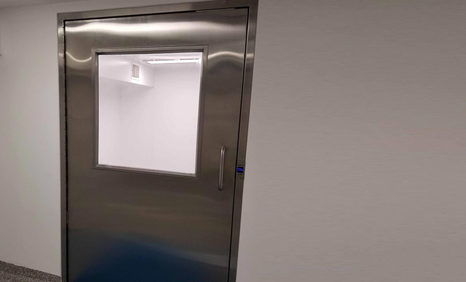 A stainless steel door with a window in a room.