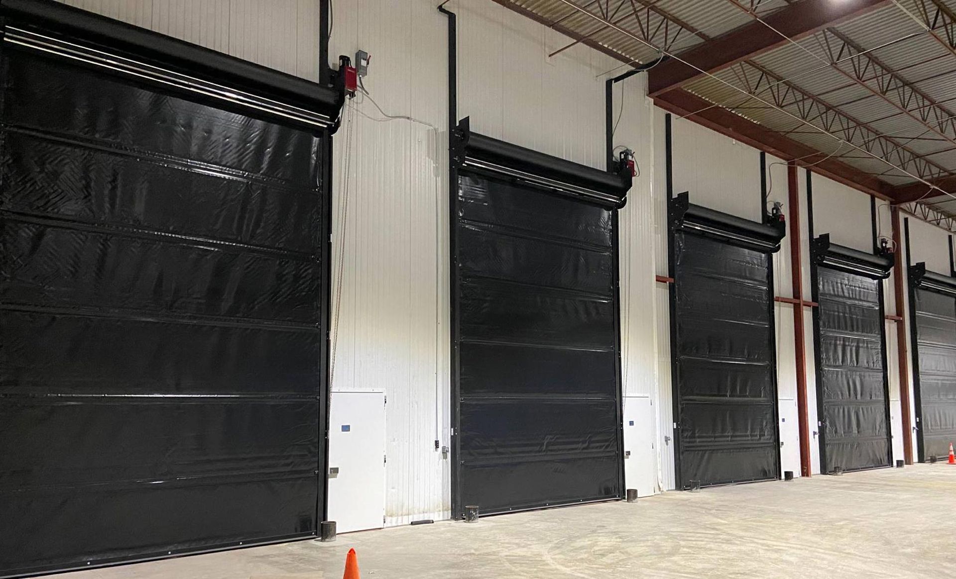 A row of black garage doors in a warehouse.