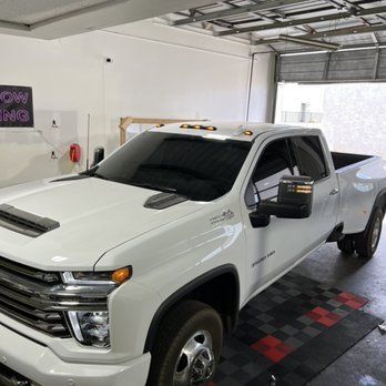 A white truck is parked inside the shop's garage