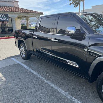 A black truck is parked in a parking lot in front of a building