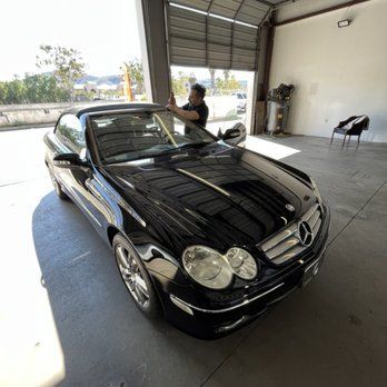 A man is working on a black car in a garage
