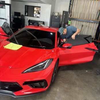 A man is working on a red sports car in a garage