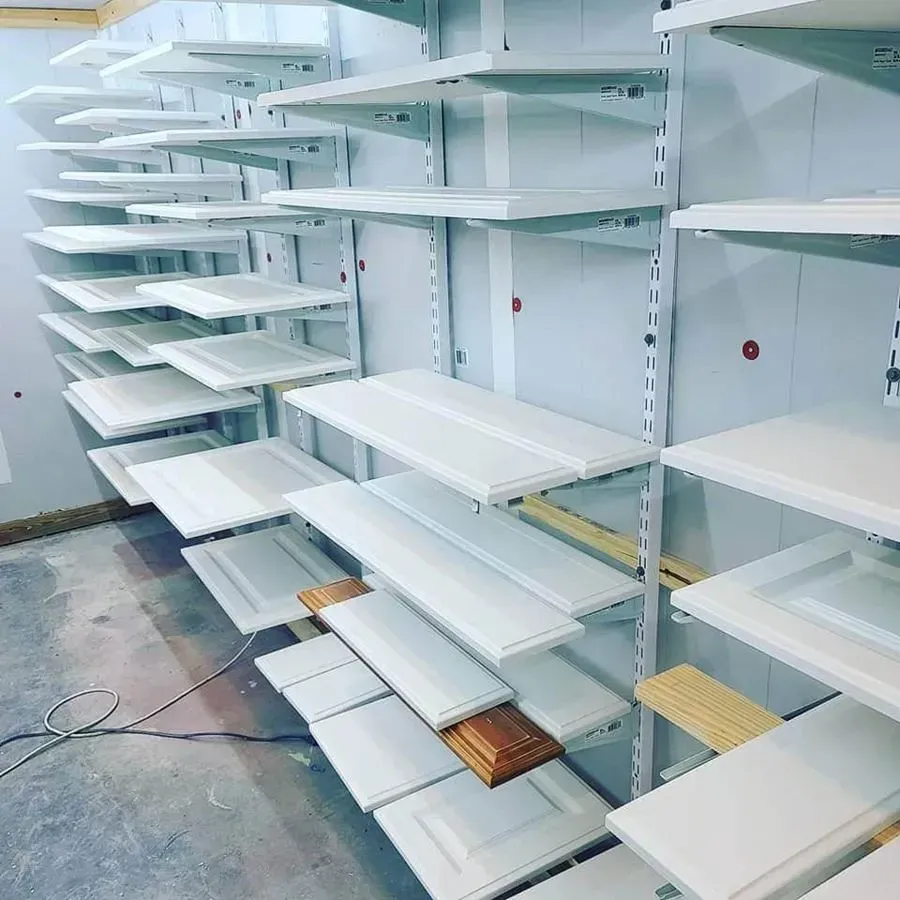 White cabinet doors drying on tiered shelves in a workshop.