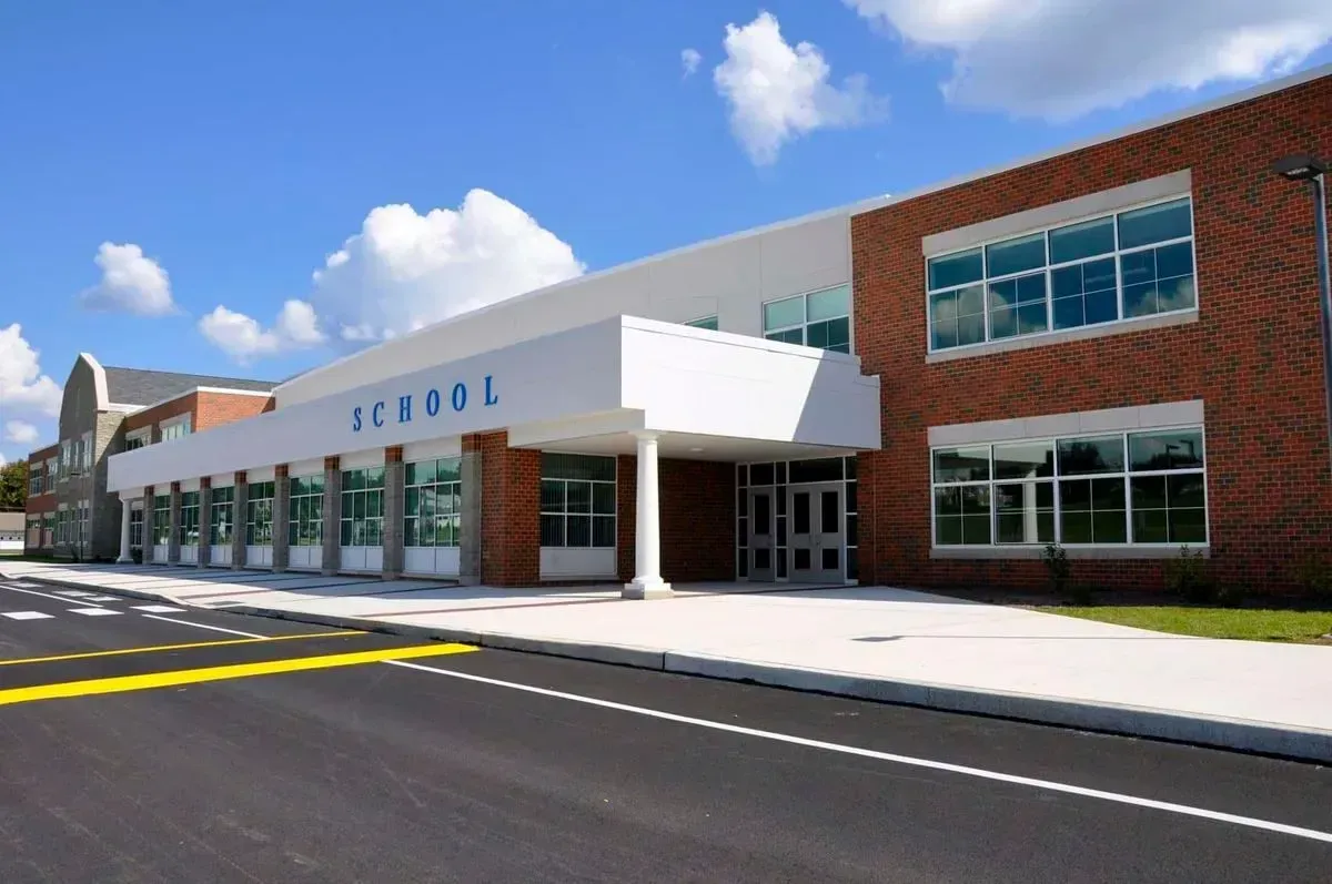 School building with brick and white exterior under a blue sky with clouds.