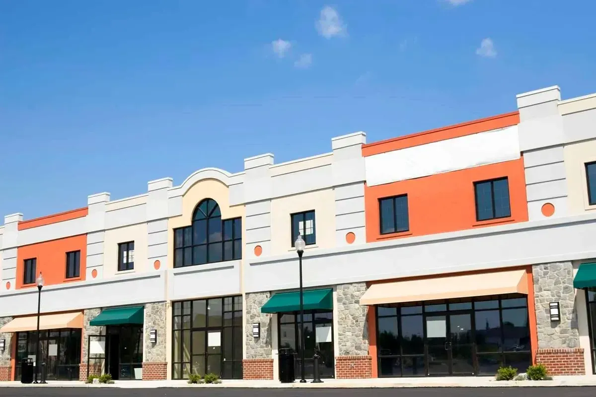 Row of multi-colored commercial buildings with awnings under a bright blue sky.
