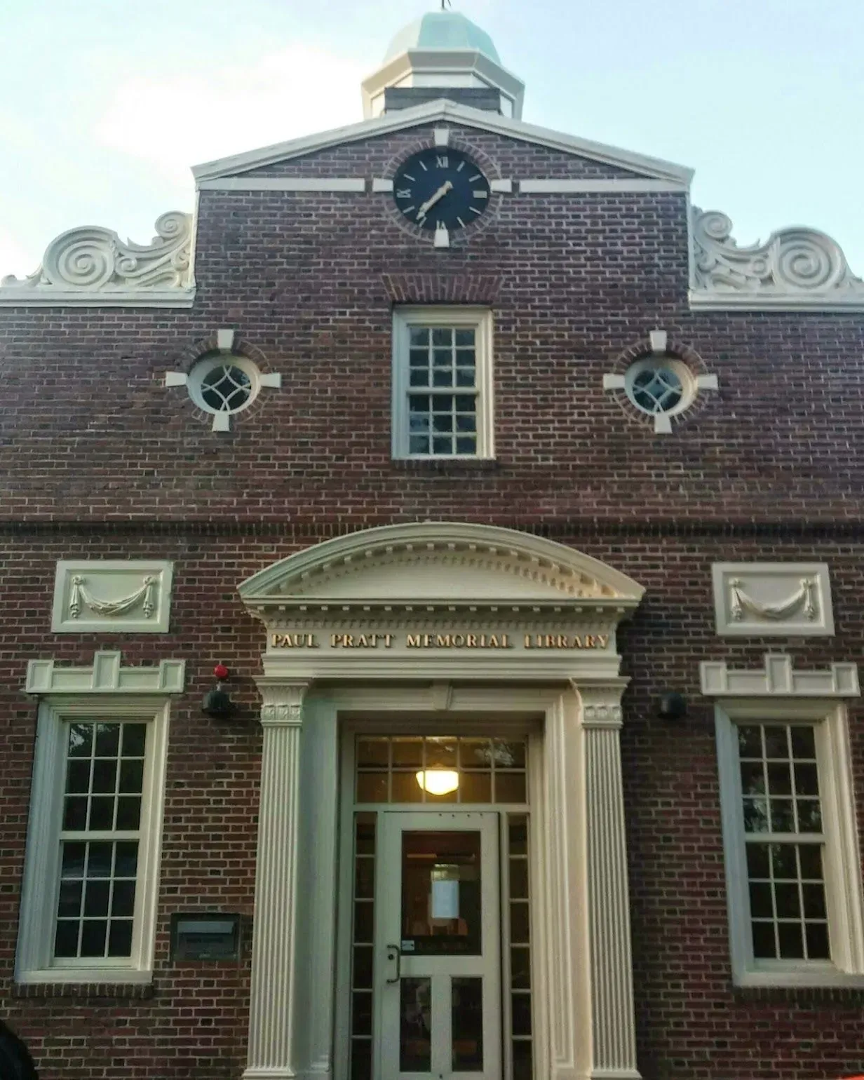 Brick building with white trim, clock, and arched doorway.