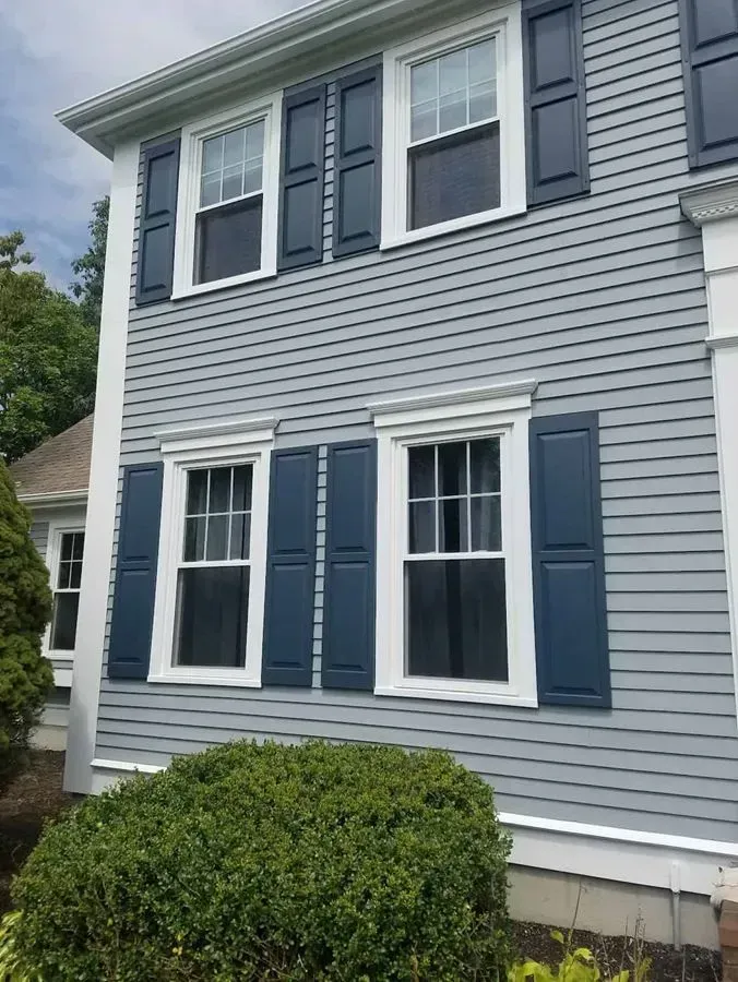 Gray clapboard house with blue shutters and white-framed windows.