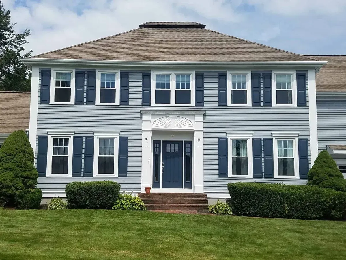 Two-story house with light blue siding, blue shutters, and a dark blue front door.