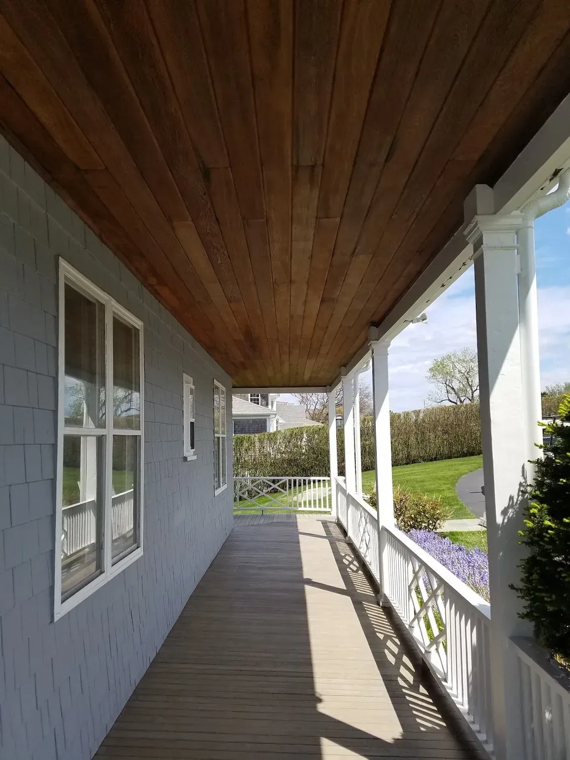 Wooden porch with gray siding, white trim, and a wood plank ceiling.