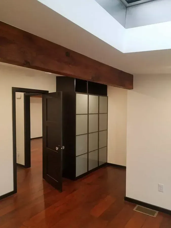 Interior view of a room with a hardwood floor, dark trim, and a built-in wardrobe with frosted glass panels.