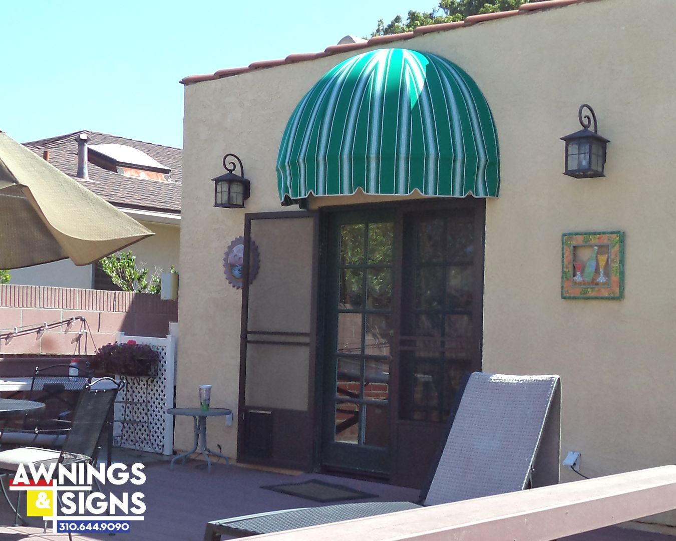 Green and white striped dome awning over a doorway on a sunny patio.