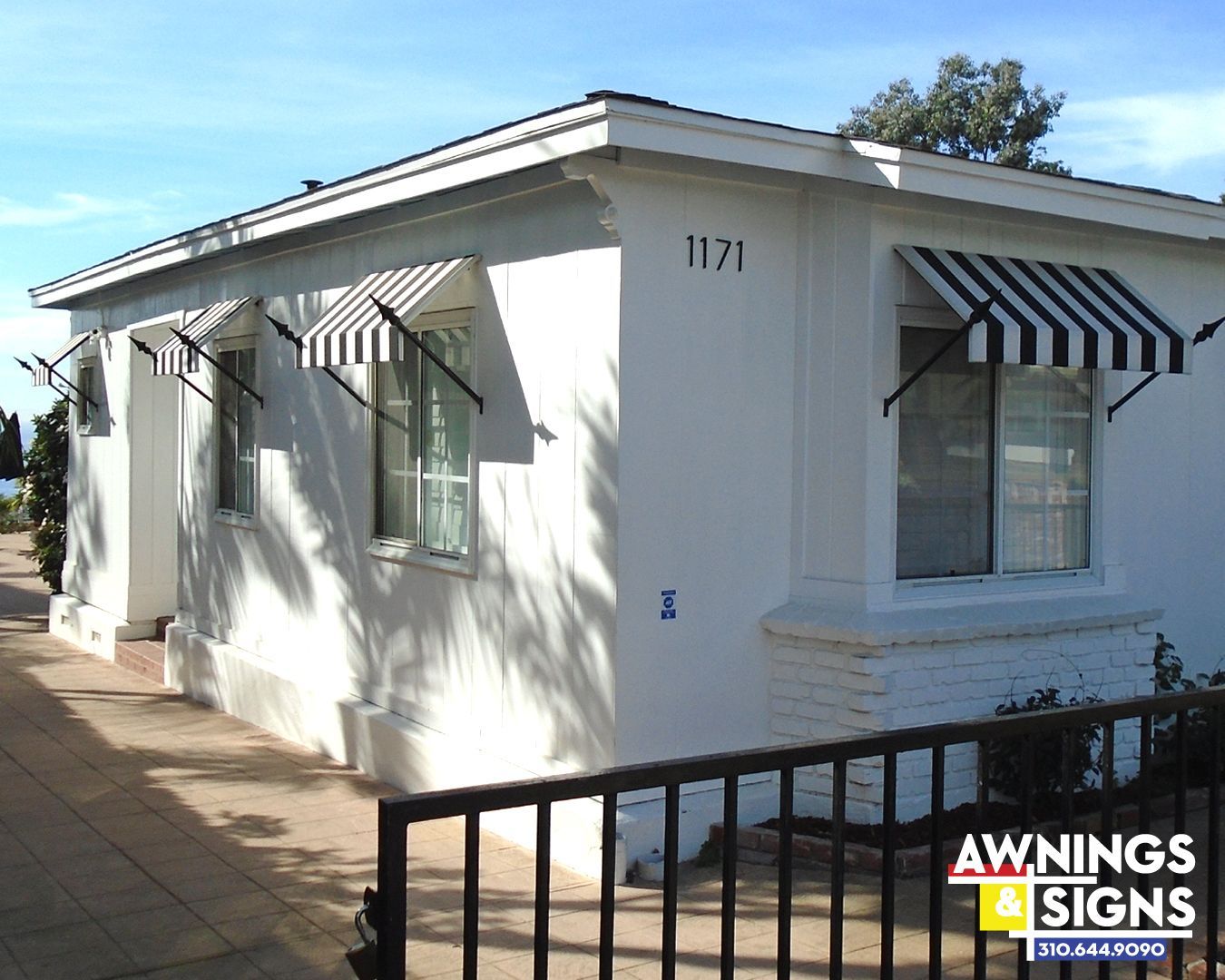 White building with black and white striped awnings over windows, number 1171 visible.