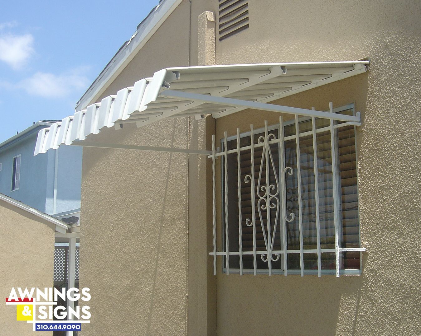 White awning over barred window on beige building.