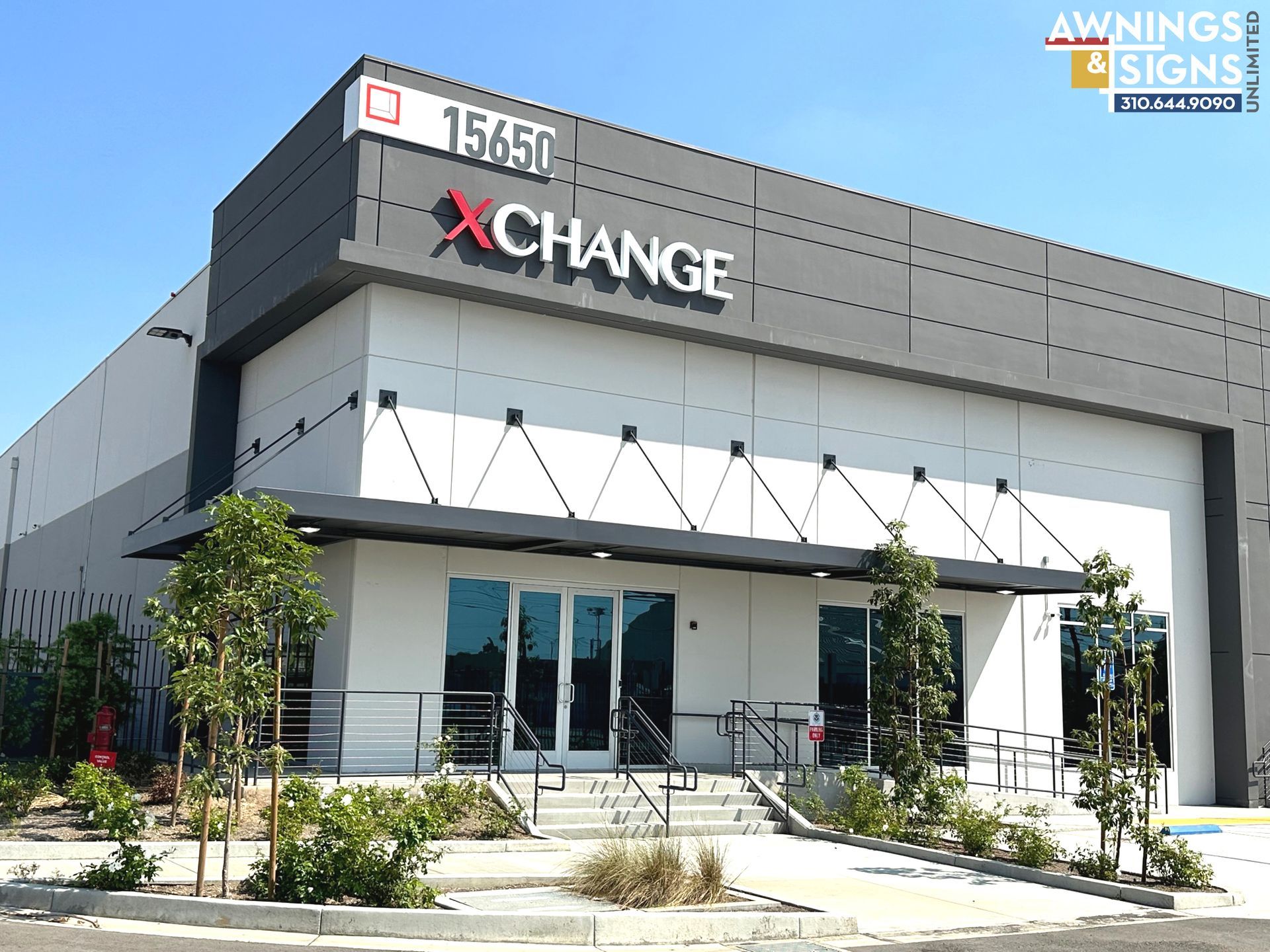 Building exterior with XCHANGE sign and address 15650 on a sunny day. Modern design, windows, awning.