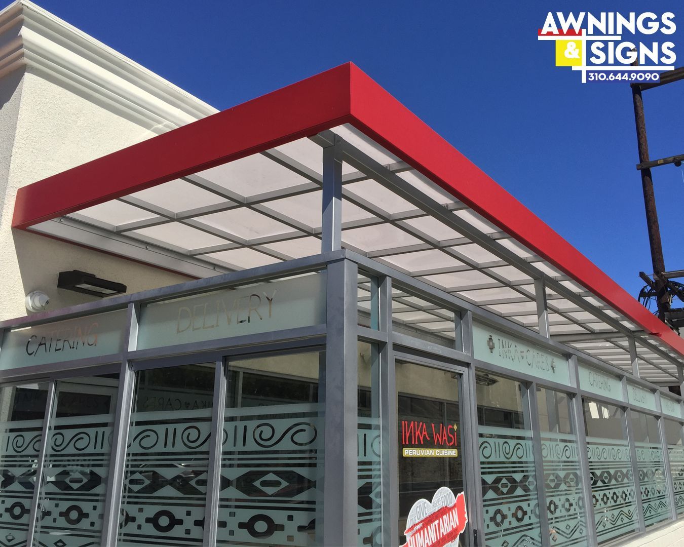 Red-topped awning over a restaurant entrance with glass windows featuring patterned designs; Awning & Signs logo in corner.