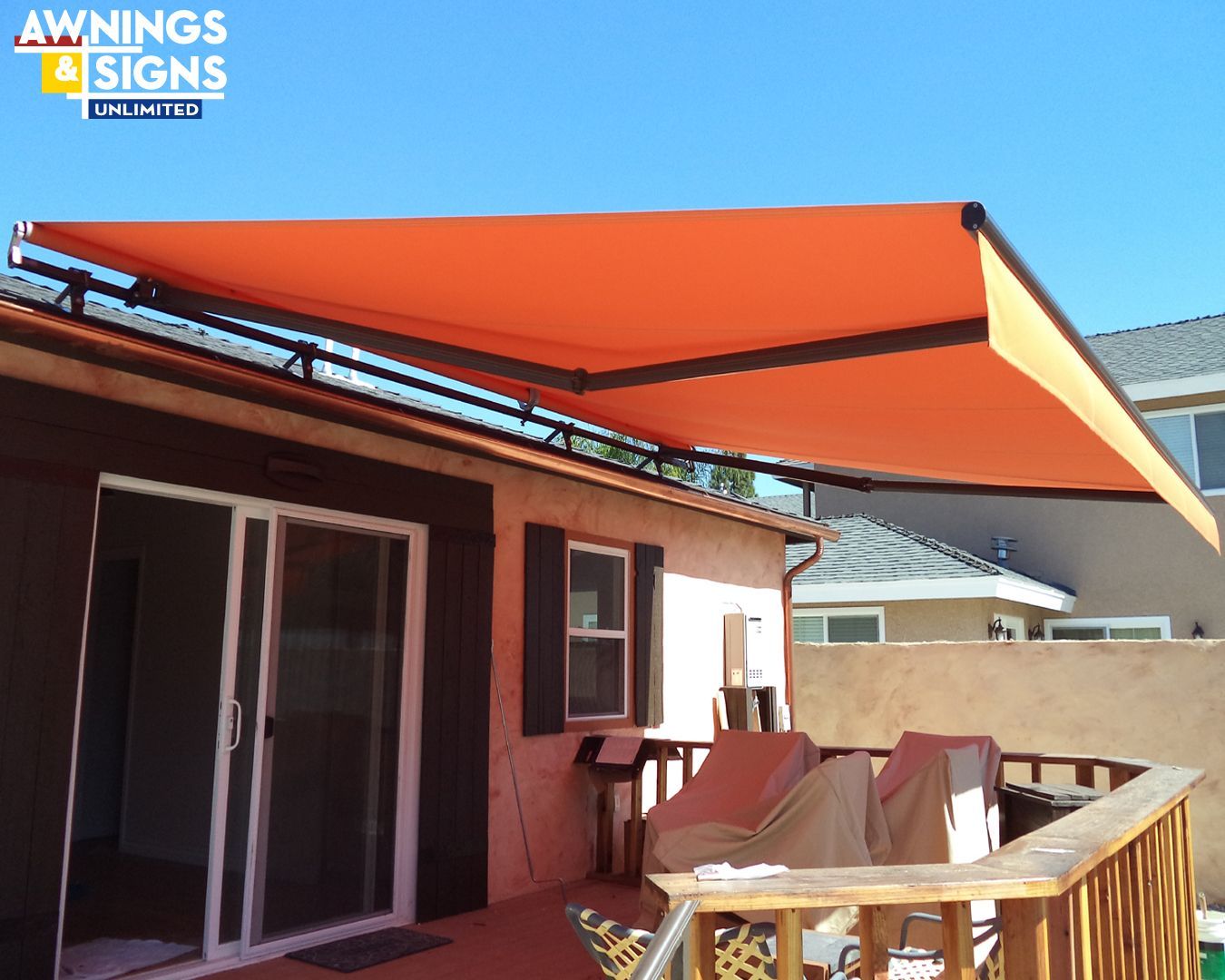 Orange retractable awning over a deck on a sunny day.