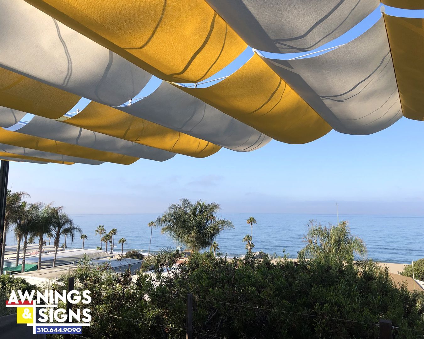 Yellow and white striped awning over beach and ocean view.