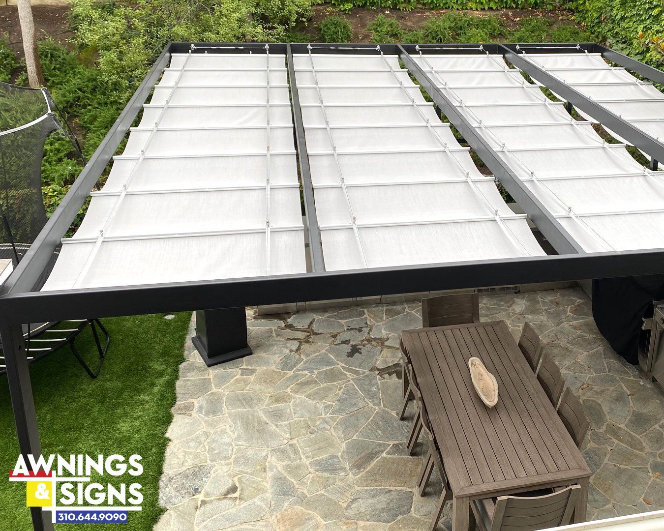 Pergola with retractable shades over a patio with a table and chairs.