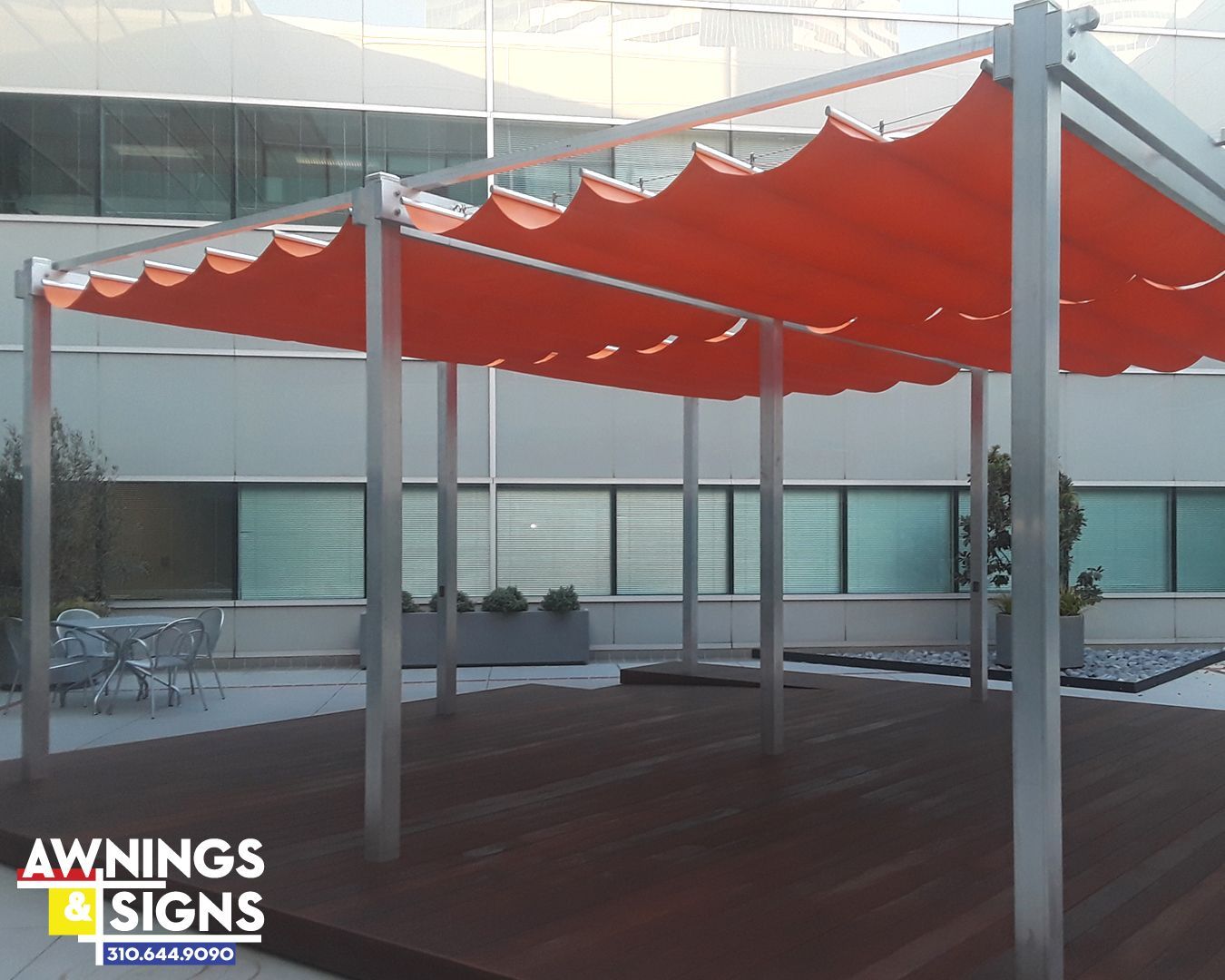 Orange awning over a wooden deck, supported by silver metal poles.