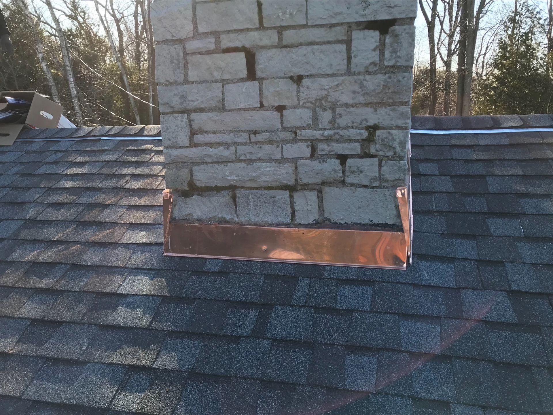 A brick chimney on top of a roof with a copper trim